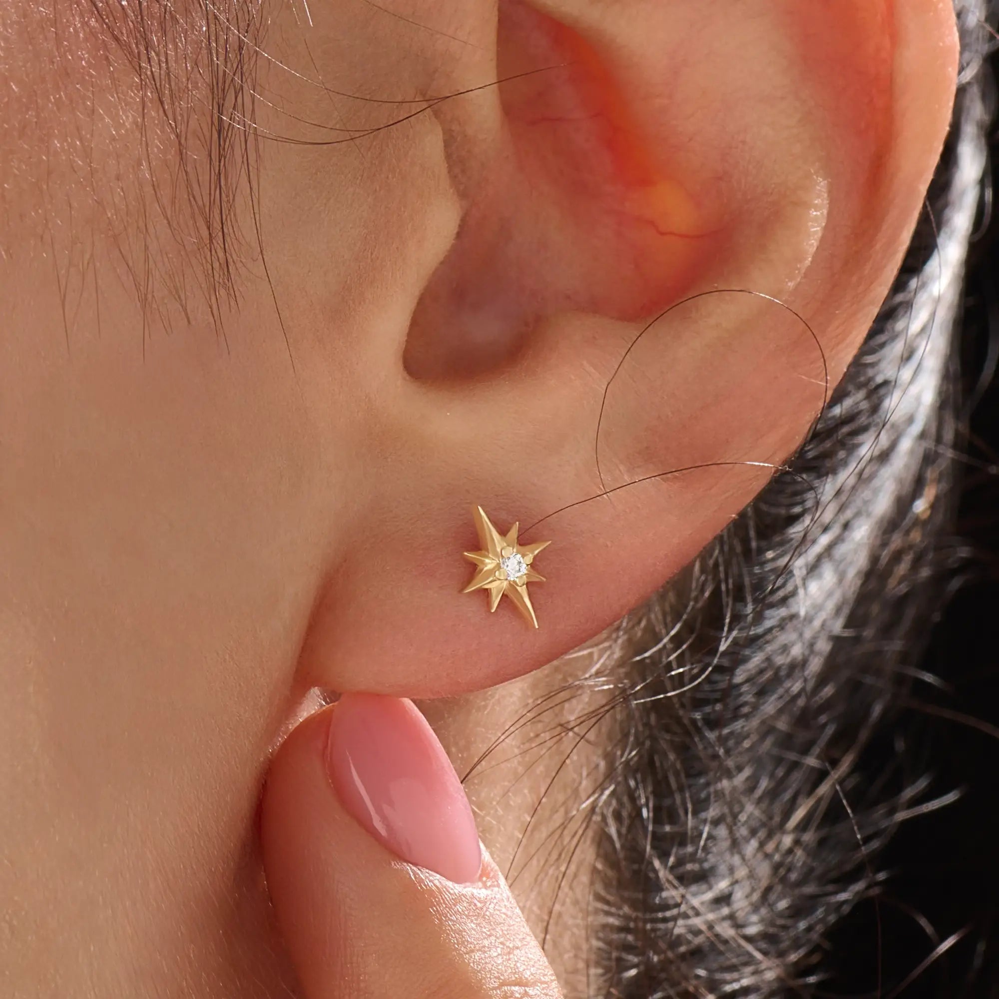 Model wearing 14k gold vermeil star stud earrings with a radiant starburst silhouette that brings subtle shine and celestial beauty to everyday style.
