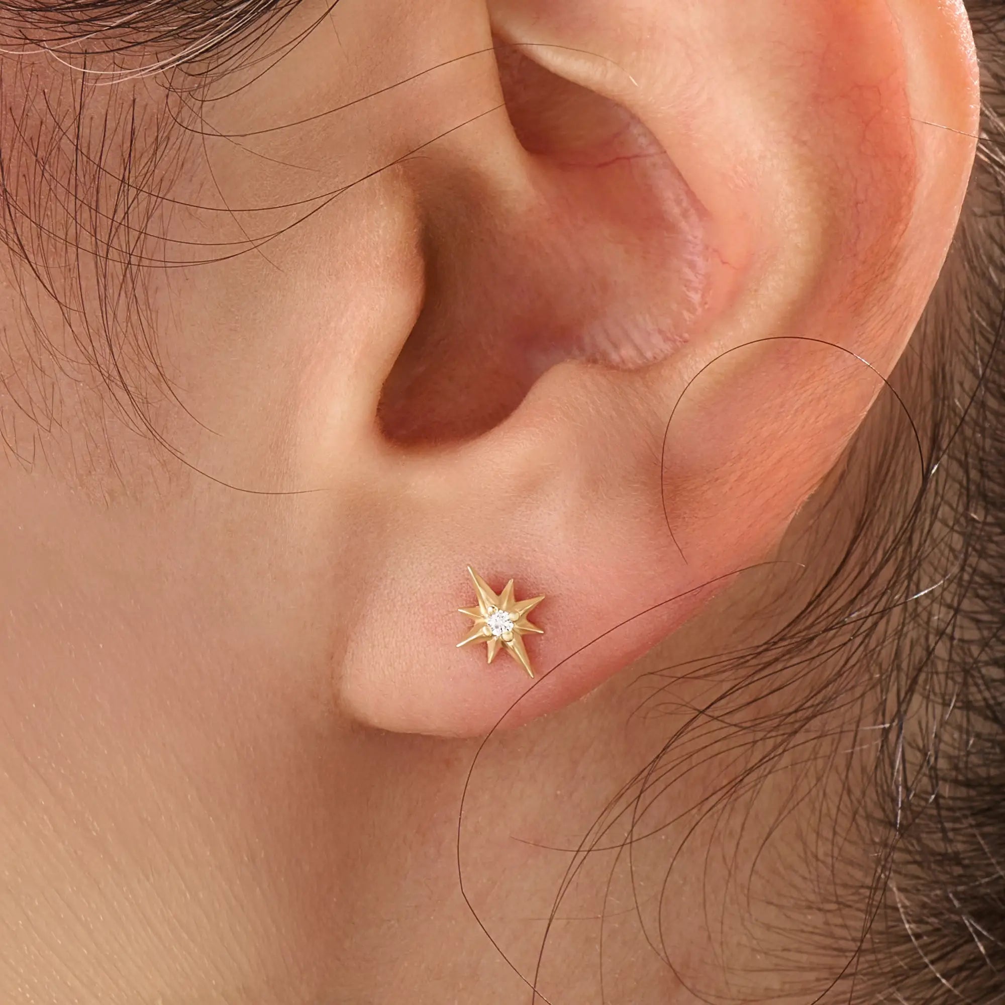 Model wearing 14k gold vermeil star stud earrings with a radiant starburst silhouette that brings subtle shine and celestial beauty to everyday style.
