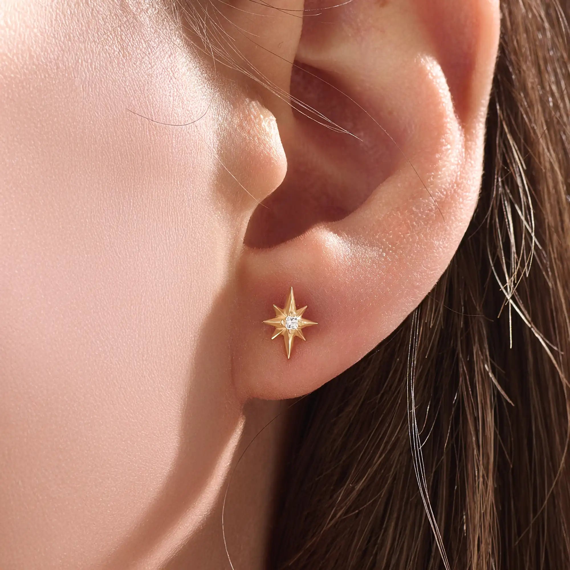 Model wearing 14k gold vermeil star stud earrings with a radiant starburst silhouette that brings subtle shine and celestial beauty to everyday style.
