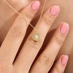 Model wearing a 14k gold vermeil starburst coin necklace featuring a minimalist round pendant with a luminous cubic zirconia centerpiece for a subtle celestial charm.
