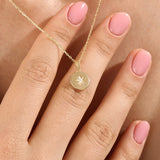 Model wearing a 14k gold vermeil starburst coin necklace featuring a minimalist round pendant with a luminous cubic zirconia centerpiece for a subtle celestial charm.
