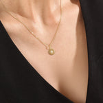 Model wearing a 14k gold vermeil starburst coin necklace featuring a minimalist round pendant with a luminous cubic zirconia centerpiece for a subtle celestial charm.
