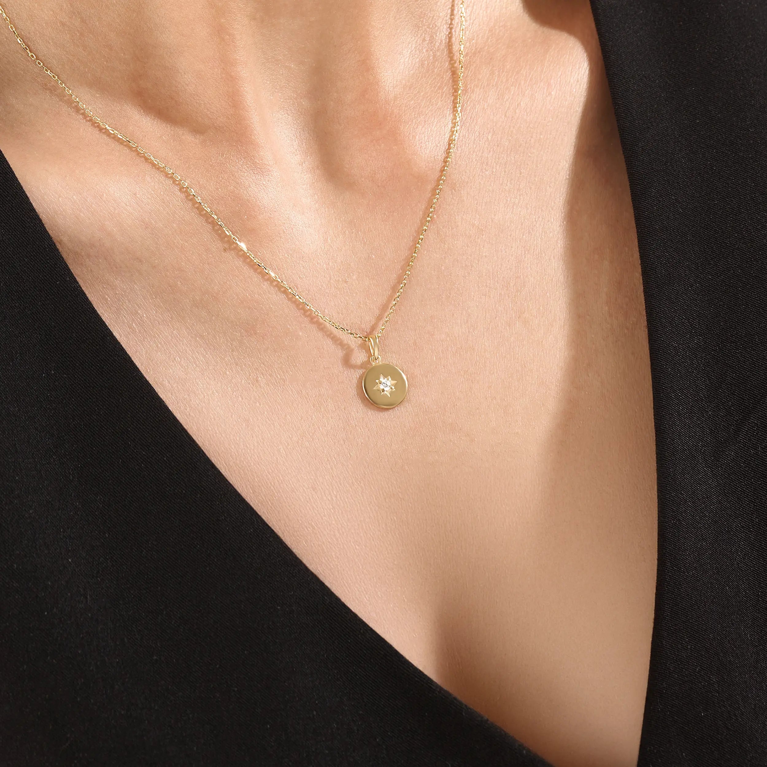Model wearing a 14k gold vermeil starburst coin necklace featuring a minimalist round pendant with a luminous cubic zirconia centerpiece for a subtle celestial charm.
