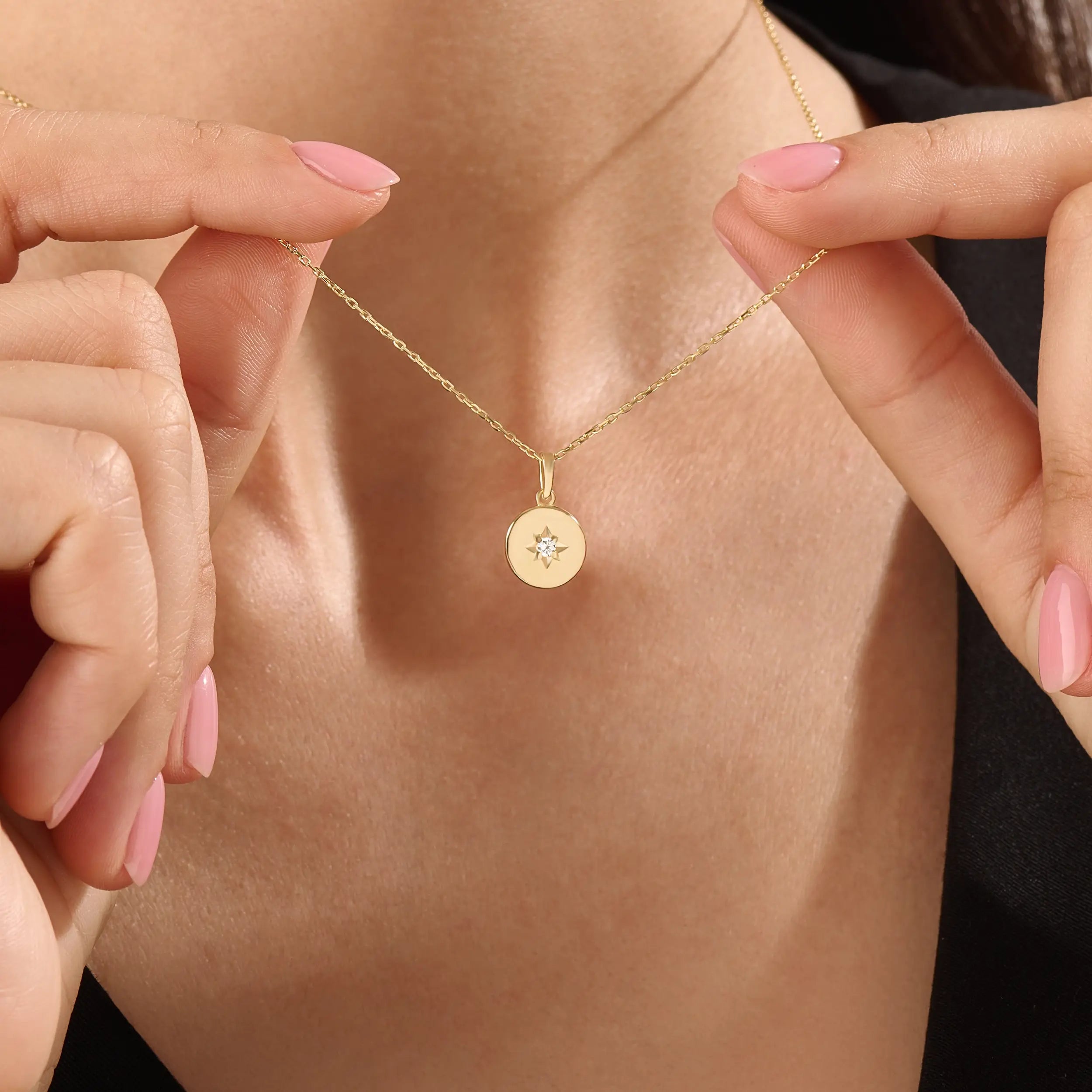 Model wearing a 14k gold vermeil starburst coin necklace featuring a minimalist round pendant with a luminous cubic zirconia centerpiece for a subtle celestial charm.
