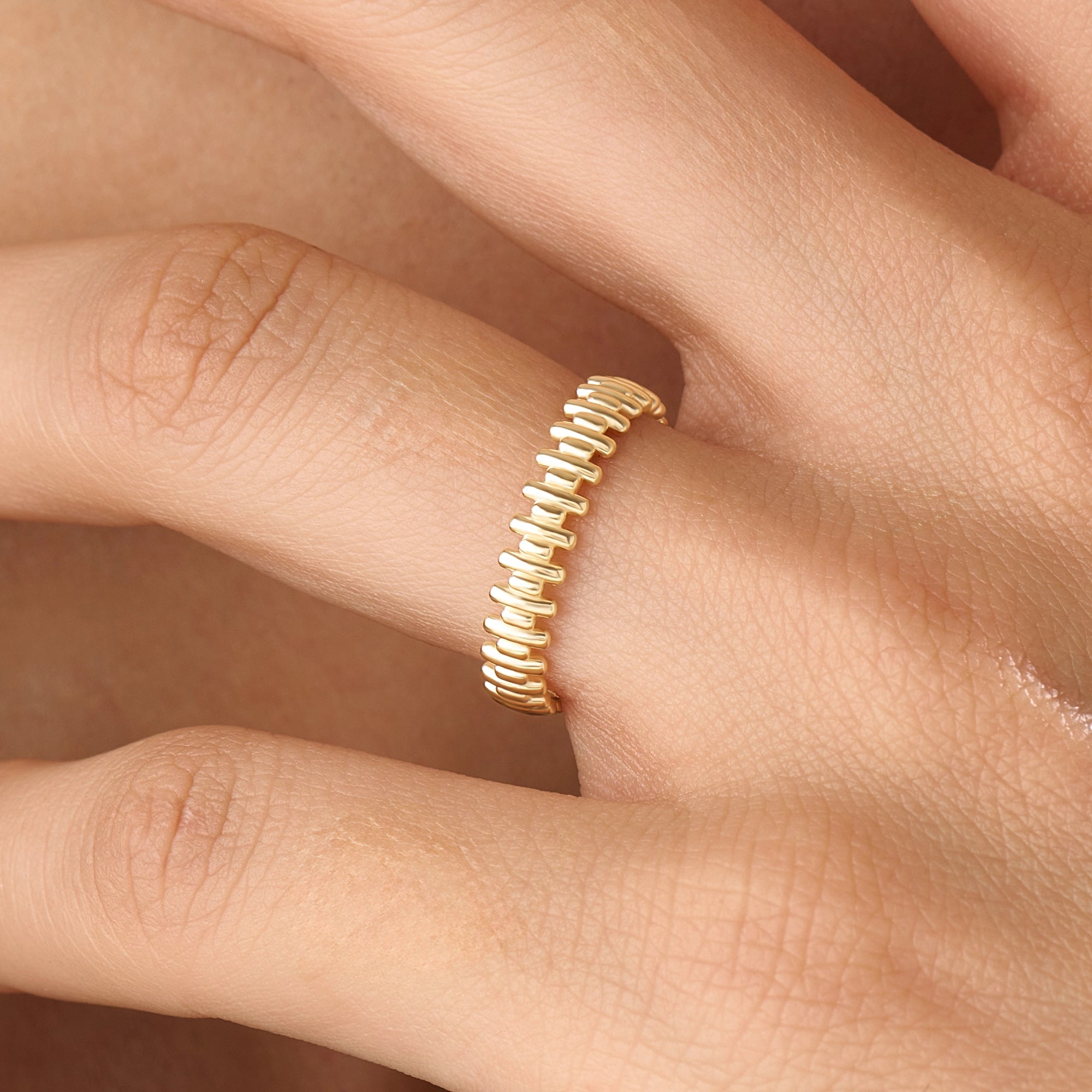 Model wearing a 14k gold vermeil striped ring with its reflective beaded pattern catching the light, adding a refined touch to any look.
