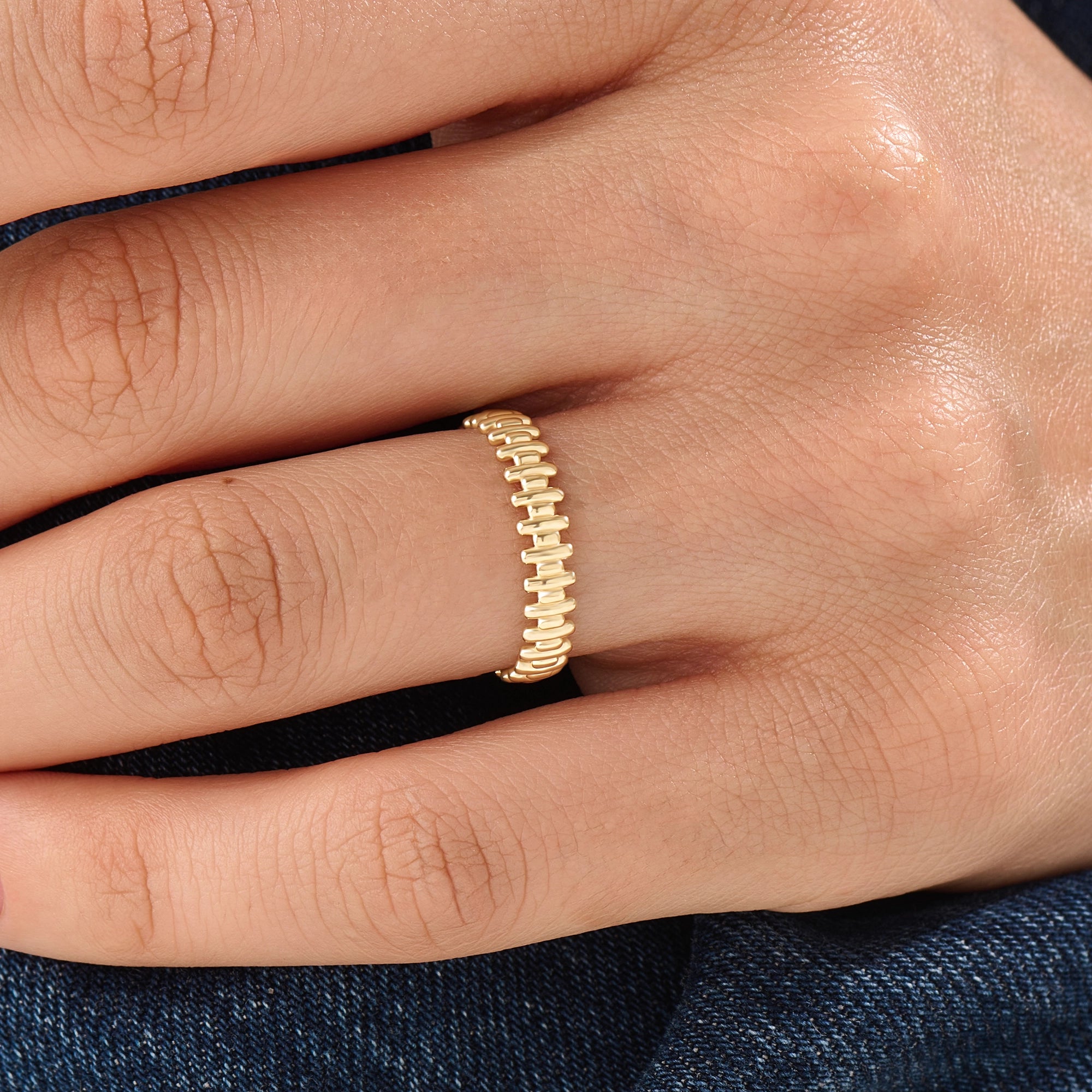 Model wearing a 14k gold vermeil striped ring with its reflective beaded pattern catching the light, adding a refined touch to any look.
