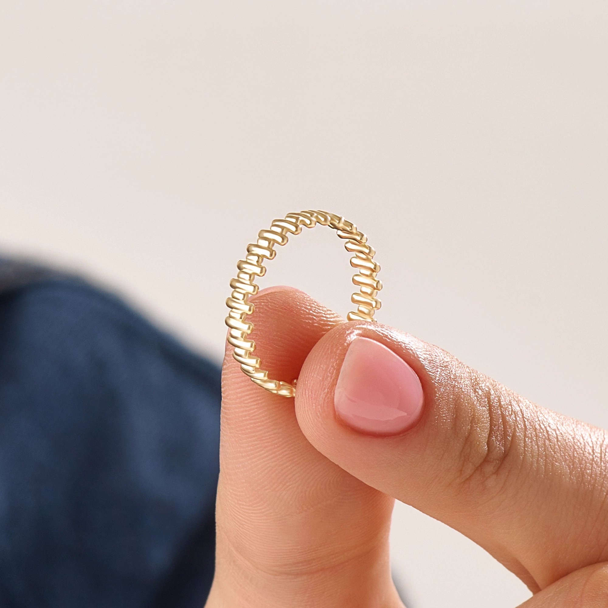 Model wearing a 14k gold vermeil striped ring with its reflective beaded pattern catching the light, adding a refined touch to any look.
