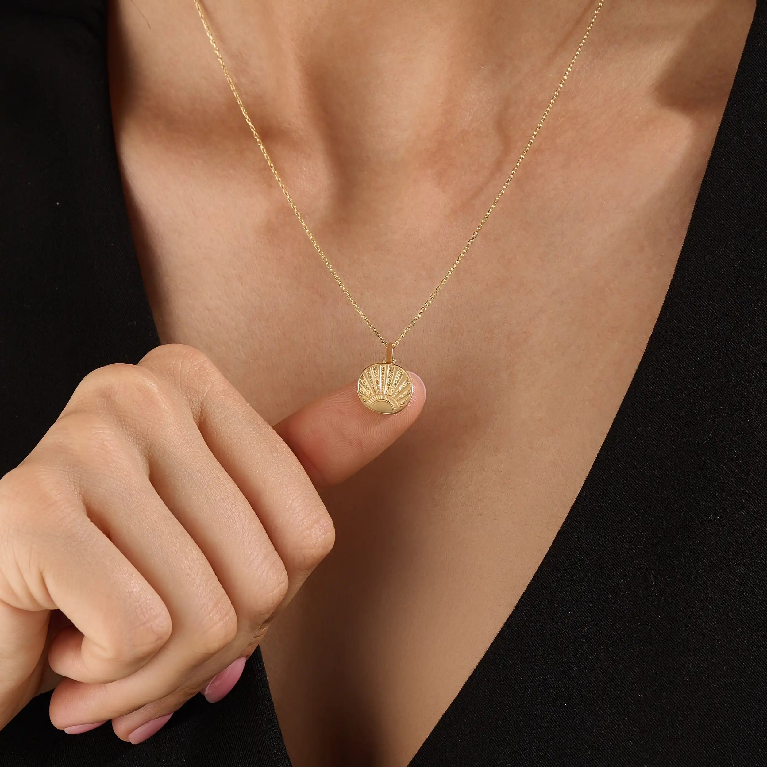Model wearing a 14k gold vermeil sunrise coin necklace featuring a radiant engraved sun pendant that adds a golden touch of warmth and elegance to any outfit.
