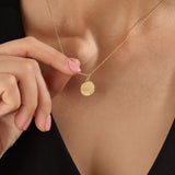 Model wearing a 14k gold vermeil sunrise coin necklace featuring a radiant engraved sun pendant that adds a golden touch of warmth and elegance to any outfit.
