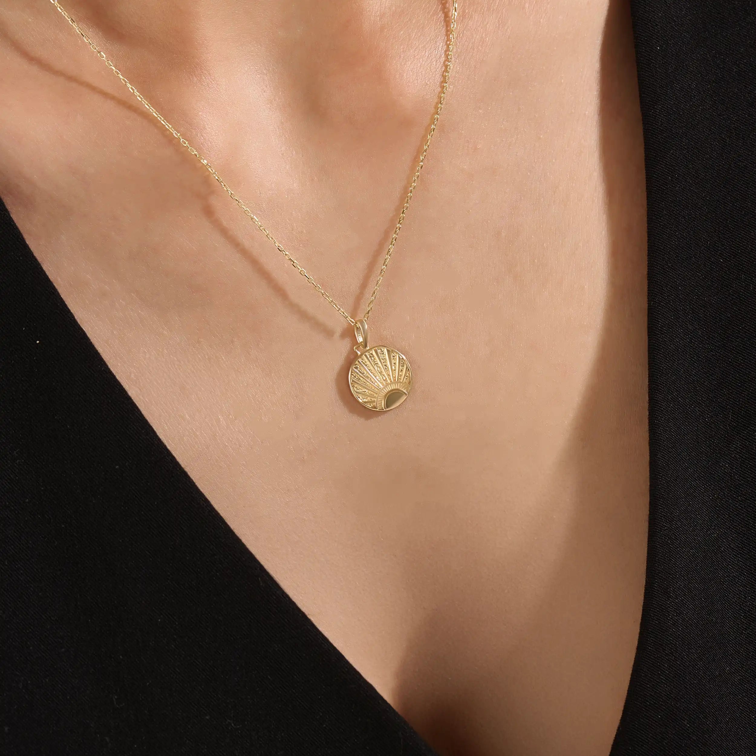 Model wearing a 14k gold vermeil sunrise coin necklace featuring a radiant engraved sun pendant that adds a golden touch of warmth and elegance to any outfit.
