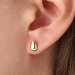 Model wearing 14k gold vermeil teardrop stud earrings that capture light with their glossy, rounded teardrop design for a sophisticated finish.
