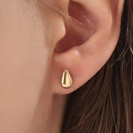 Model wearing 14k gold vermeil teardrop stud earrings that capture light with their glossy, rounded teardrop design for a sophisticated finish.
