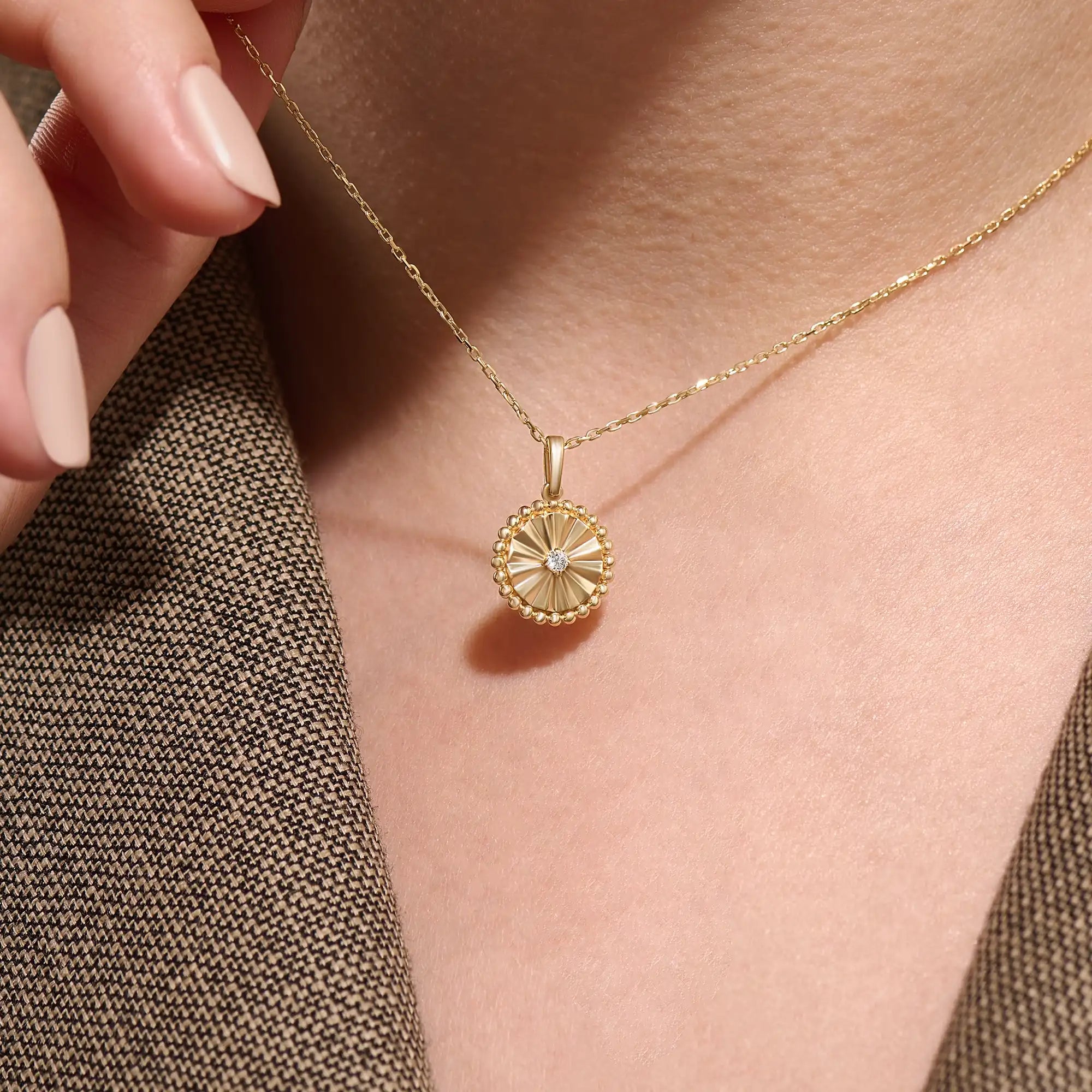 Model wearing a 14k gold vermeil textured coin necklace featuring a radiant beaded pendant with a central cubic zirconia, blending vintage charm with modern elegance.
