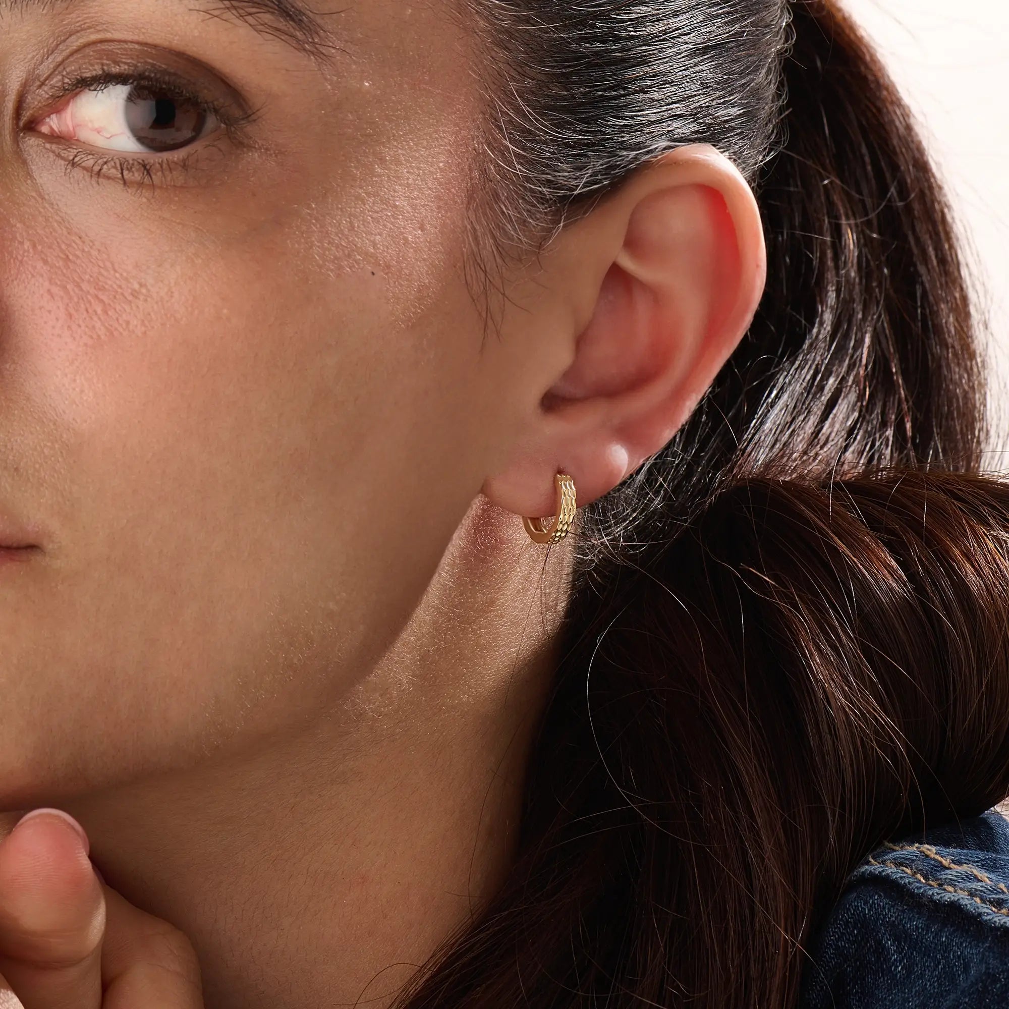 Model wearing 14k gold vermeil textured hoop earrings showcasing their radiant hammered finish that offers a touch of artisanal charm and timeless sophistication.
