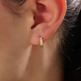 Model wearing 14k gold vermeil textured hoop earrings showcasing their radiant hammered finish that offers a touch of artisanal charm and timeless sophistication.
