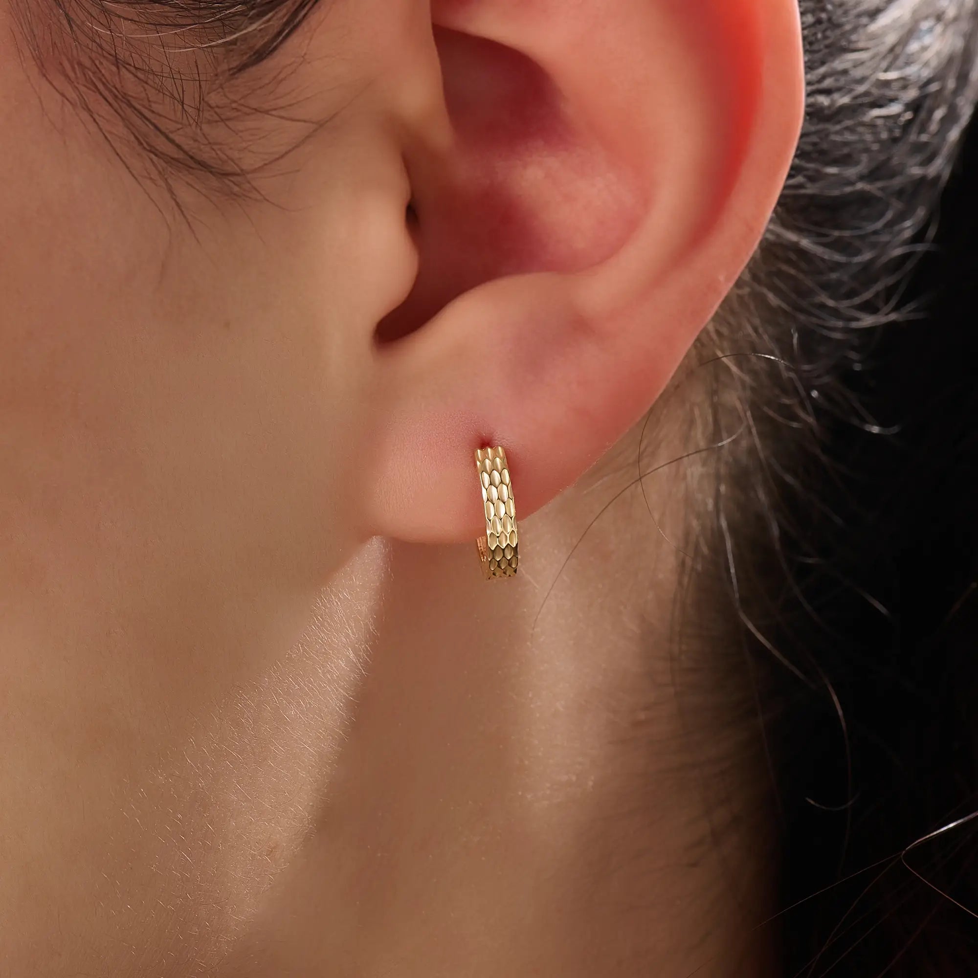 Model wearing 14k gold vermeil textured hoop earrings showcasing their radiant hammered finish that offers a touch of artisanal charm and timeless sophistication.
