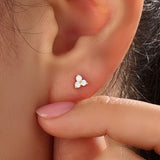 Model wearing 14k gold vermeil tiny trio earrings featuring a delicate cluster of three sparkling stones, perfect for layering or daily wear.
