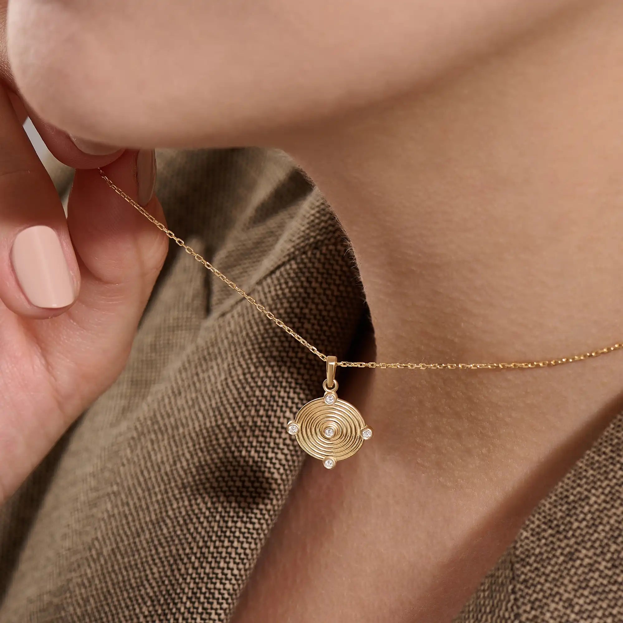 Model wearing a 14k gold vermeil unique round necklace featuring a dimensional circular pendant with radiant concentric rings and cubic zirconia accents for refined brilliance.
