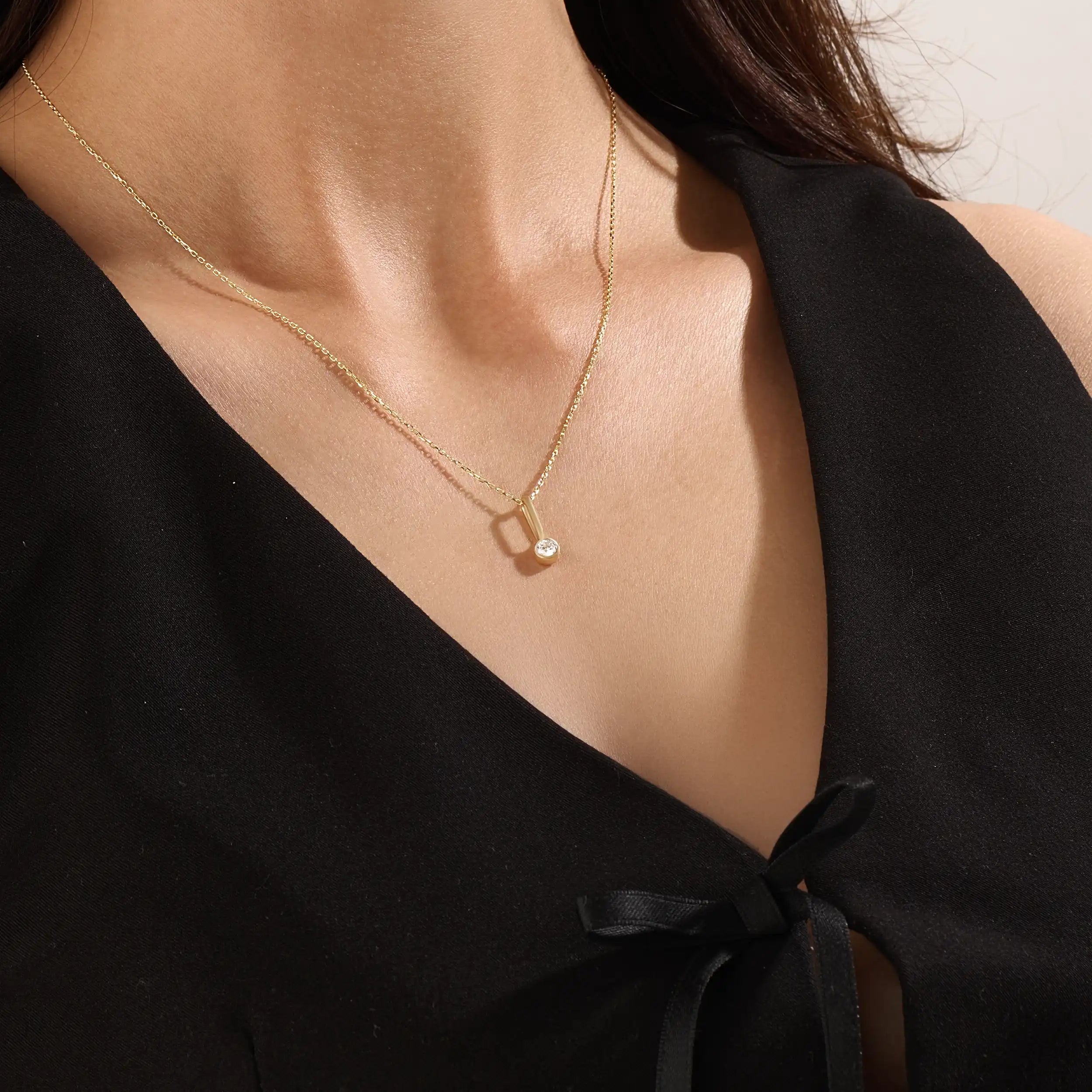 Model wearing a 14k gold vermeil unique solo necklace featuring a delicate chain and minimalist pendant with a single sparkling cubic zirconia, perfect for everyday refinement.
