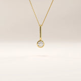 Side view of 14k gold vermeil unique solo necklace highlighting the elongated bail and brilliant round cubic zirconia centerpiece in a clean modern design.
