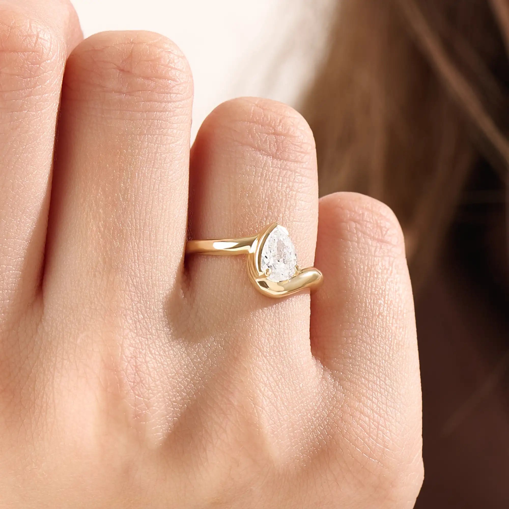 Model wearing a 14k gold vermeil wavy pear ring, showcasing its elegant wave design and radiant cubic zirconia gemstone with refined shine.

