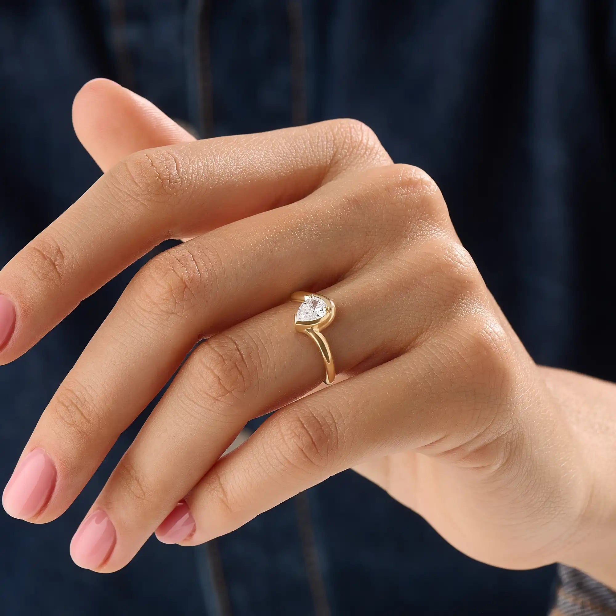 Model wearing a 14k gold vermeil wavy pear ring, showcasing its elegant wave design and radiant cubic zirconia gemstone with refined shine.

