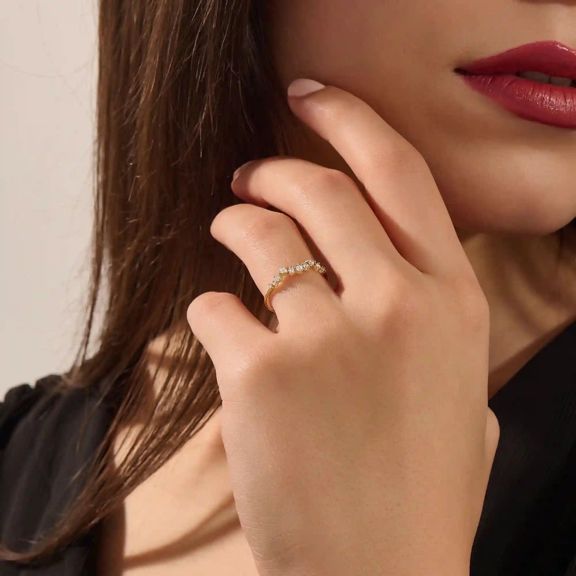 Close-up of a model’s hand wearing a 14k yellow gold pavé ring with alternating moissanite stone sizes.
