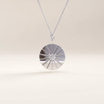 Silver vermeil coin necklace showcasing a circular pendant with a sunburst engraving and a sparkling stone centerpiece, blending elegance and modern charm.
