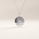 Silver vermeil coin necklace showcasing a circular pendant with a sunburst engraving and a sparkling stone centerpiece, blending elegance and modern charm.
