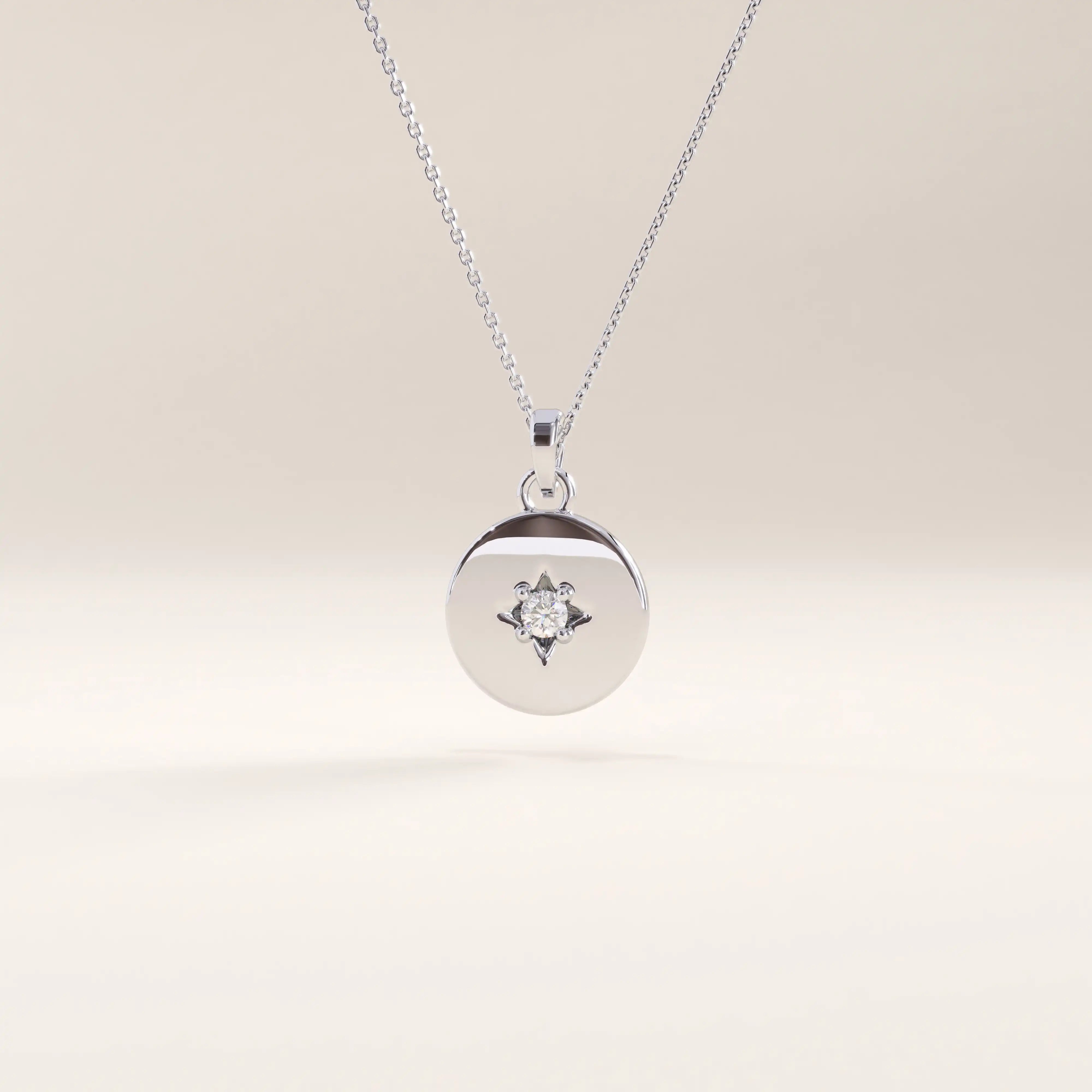 Silver vermeil starburst coin necklace with a sleek circular medallion showcasing a delicate starburst detail centered by a clear cubic zirconia stone.
