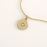 14k gold vermeil starburst coin necklace featuring a polished round pendant adorned with a radiant star engraving and a sparkling cubic zirconia at the center.
