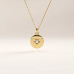 14k gold vermeil starburst coin necklace featuring a polished round pendant adorned with a radiant star engraving and a sparkling cubic zirconia at the center.
