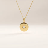 14k gold vermeil starburst coin necklace featuring a polished round pendant adorned with a radiant star engraving and a sparkling cubic zirconia at the center.

