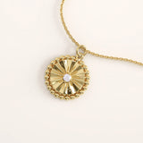 14k gold vermeil textured coin necklace featuring a radiant sunburst pattern pendant bordered with delicate beaded detailing and a central cubic zirconia for a brilliant finish.

